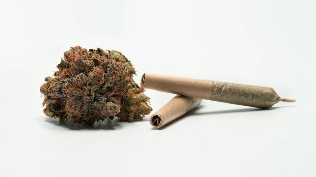 Close-up of Chem X cannabis bud with rolling papers on a white background.