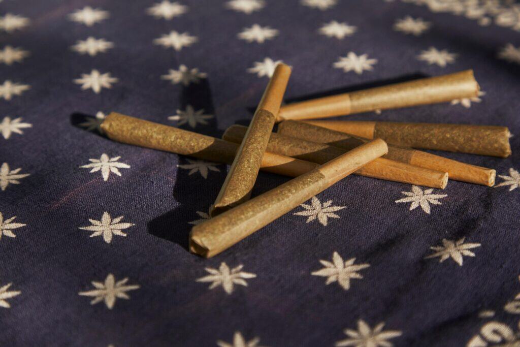 Apple Banana Gelato cannabis pre-rolls on dark fabric background.