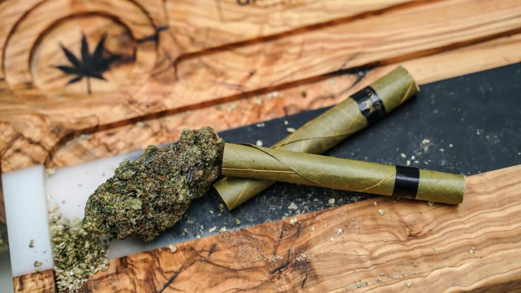 Hand-rolled G Code strain cannabis joint on wooden surface.