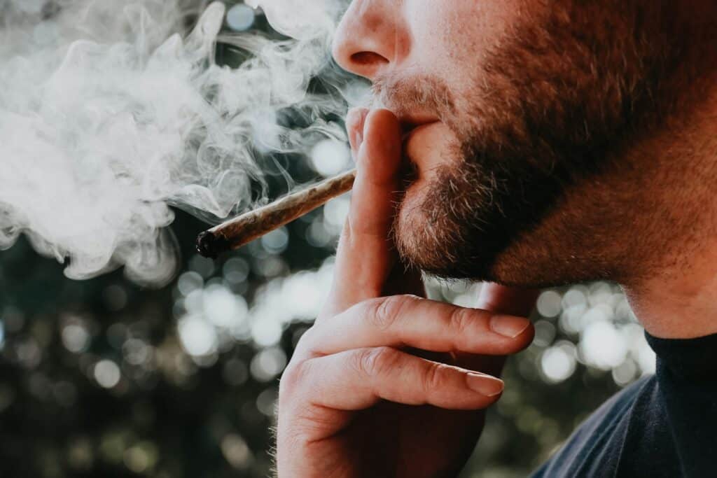 Man smoking Truffle Berry cannabis strain with smoke around his face.