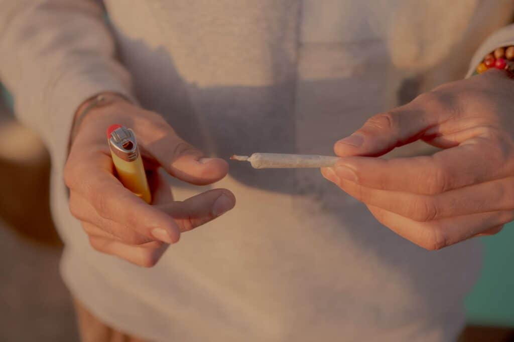 Person rolling a blunt with a lighter in hand, preparing for smoking.